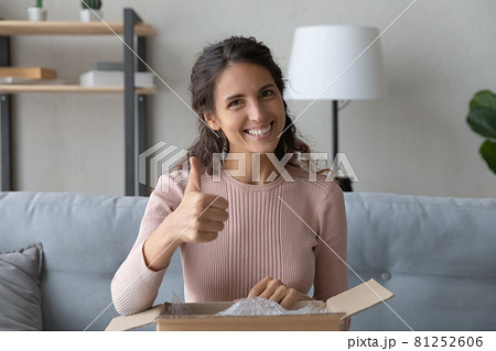 Woman sit with parcel box feels satisfied showing thumbs up Woman sit with parcel box feels satisfied showing thumbs up 81252606