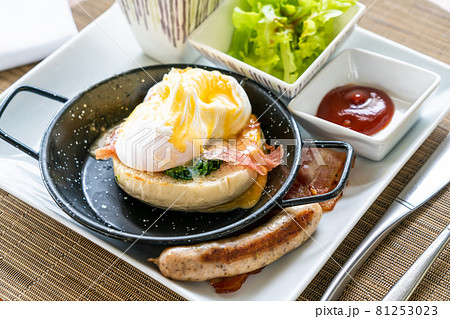 Egg benedict with bacon and sausage - delicious american breakfast 81253023
