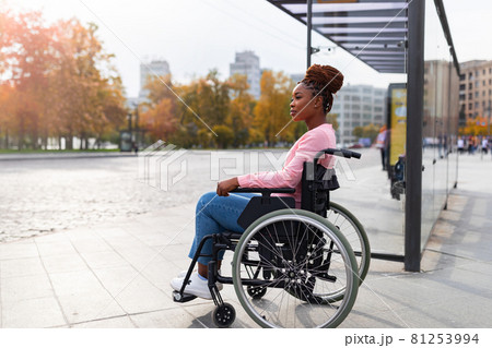 Black paraplegic woman in wheelchair waiting on bus stop, cannot board vehicle suitable for handicapped persons 81253994