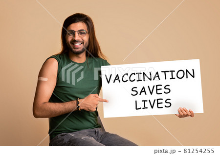 Smiling middle-eastern guy pointing at board Vaccination Saves Lives Smiling middle-eastern guy pointing at board Vaccination Saves Lives 81254255