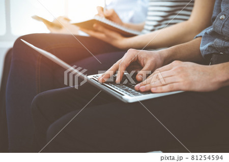 Group of casual dressed business people working at meeting or conference in sunny office, close-up of hands. Businessman using laptop computer Group of casual dressed business people working at meeting or conference in sunny office, close-up of hands. Businessman using laptop computer 81254594