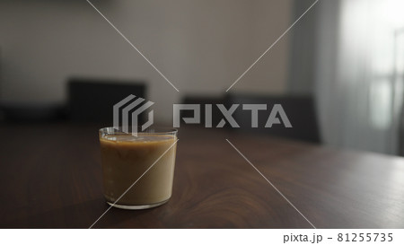 cold brew coffee with milk and ice ball in tumbler glass on walnut table 81255735