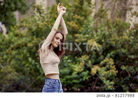 Elegant young woman is dancing in city garden. 81257988