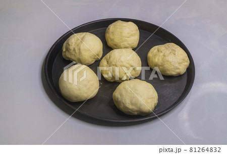 Flour dough balls resting on an oily surface on the round pizza plate. Dough balls have perfectly risen. Hand kneaded the dough for making homemade pastry buns to bake in the oven. Flour dough balls resting on an oily surface on the round pizza plate. Dough balls have perfectly risen. Hand kneaded the dough for making homemade pastry buns to bake in the oven. 81264832
