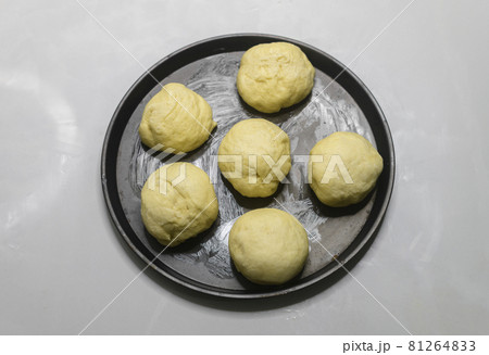 Flour dough balls resting on an oily surface on the round pizza plate overhead view. Dough balls have perfectly risen. Hand kneaded the dough for making homemade pastry buns to bake in the oven. Flour dough balls resting on an oily surface on the round pizza plate overhead view. Dough balls have perfectly risen. Hand kneaded the dough for making homemade pastry buns to bake in the oven. 81264833