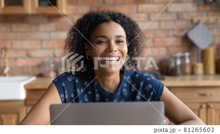 Happy millennial Black woman laughing at laptop at home Happy millennial Black woman laughing at laptop at home 81265603