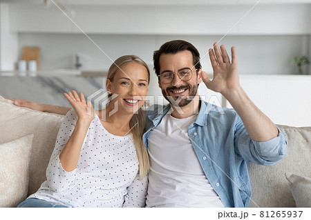 Happy millennial couple waving hello, smiling at webcam Happy millennial couple waving hello, smiling at webcam 81265937