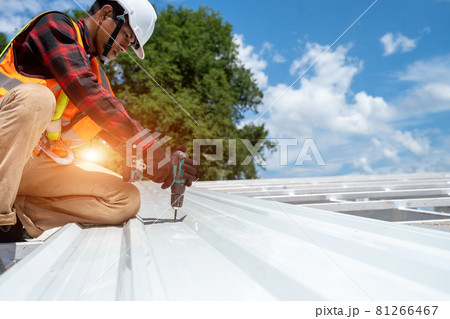 Roofer working at metal profile roof installation,Roofing tools,Electric drill used on new roofs. 81266467