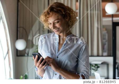 Smiling young businesswoman use cellphone texting online 81266945