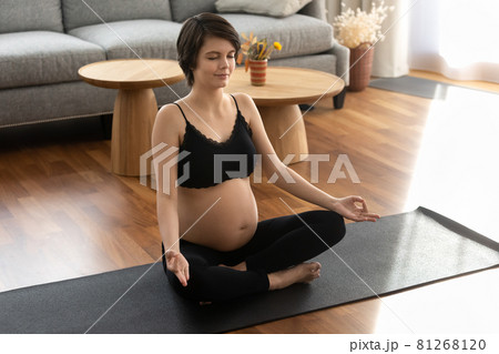 Calm pregnant woman in fitness outfit meditating at home Calm pregnant woman in fitness outfit meditating at home 81268120