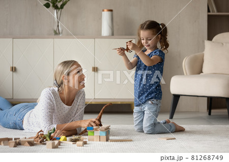 Happy mom and daughter playing with dinosaurs on warm floor, Happy mom and daughter playing with dinosaurs on warm floor, 81268749