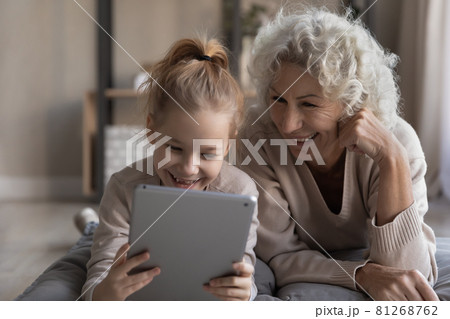 Happy old grandma and small granddaughter use tablet 81268762