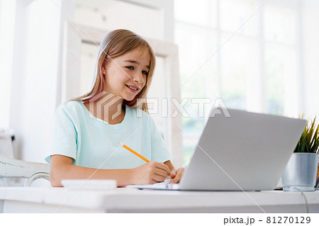 Young girl using laptop for homework at home 81270129