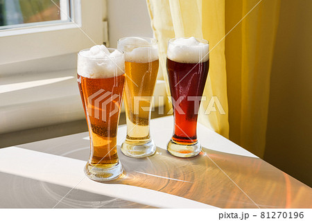 Three glasses with different sorts of beer on table 81270196