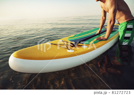 Young fit man on paddle board floating on lake. Young fit man on paddle board floating on lake. 81272723