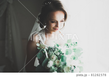 Gorgeous bride in robe posing and preparing for the wedding ceremony face in a room Gorgeous bride in robe posing and preparing for the wedding ceremony face in a room 81282378
