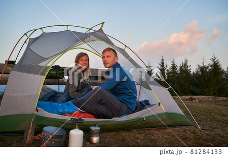 Man and woman just woken up in tent after sweet night in the open air, watching amazing view of the morning mountains. Concept of hiking, camping and relationships. 81284133