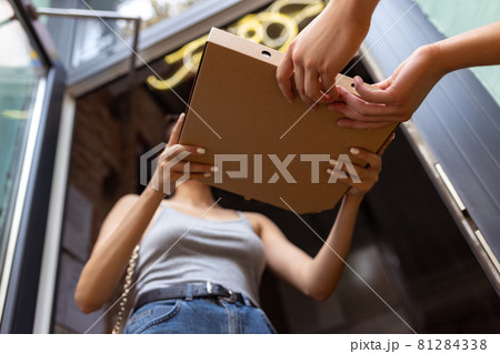 Close-up deliveryman delivers order to young girl, buyer. Work, career, different professions concept. Idea of convenience, speed, comfort, safety, service. 81284338