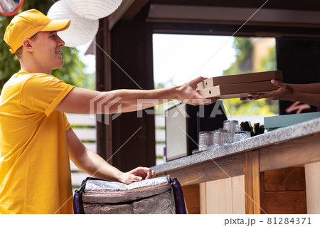 Young deliveryman in yellow uniform picking up order to clients, customers, buyers. Work, career, different professions concept. Idea of convenience, speed, comfort, safety, service. Young deliveryman in yellow uniform picking up order to clients, customers, buyers. Work, career, different professions concept. Idea of convenience, speed, comfort, safety, service. 81284371