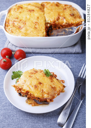 Moussaka with meat, eggplant, tomatoes, potatoes, bechamel sauce and cheese on a white plate. Traditional Greek dish. Close-up. 81284827