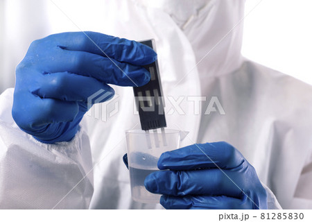 Checking the water quality. Scientist dip a test strip into a glass of water to determine the quality of the water Checking the water quality. Scientist dip a test strip into a glass of water to determine the quality of the water 81285830