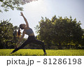 Morning sun flare with lady fitness trainer stretching showing strong abs and arms outdoors.  81286198