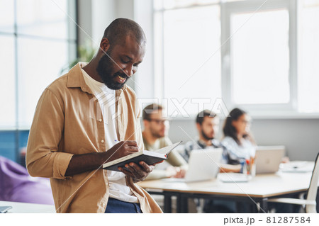 Gladsome young man writing in his note-pad 81287584