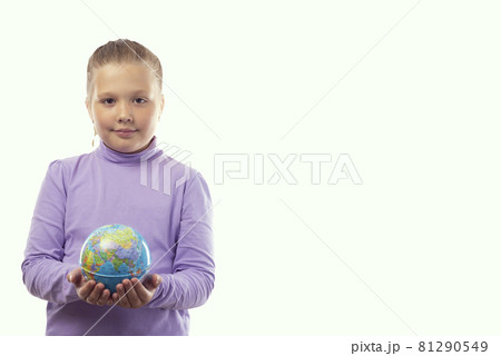 A cute little caucasian girl in a purple t-shirt holds an earth globe in her hands on a white background with a place for text 81290549