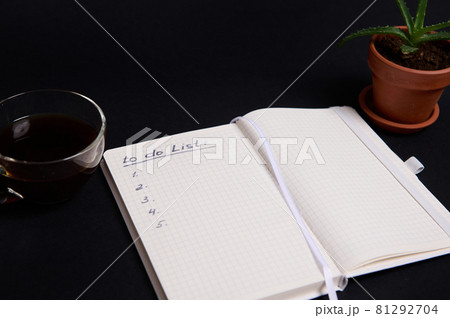 Opened notepad, organizer with list to do on blank white sheets, cup of coffee and potted succulent in clay pot, on black background with copy space. Business, Organization, Time Management concept. Opened notepad, organizer with list to do on blank white sheets, cup of coffee and potted succulent in clay pot, on black background with copy space. Business, Organization, Time Management concept. 81292704