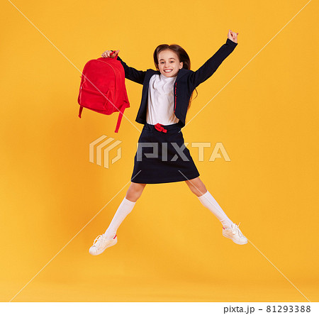 Excited schoolgirl jumping high in studio Excited schoolgirl jumping high in studio 81293388