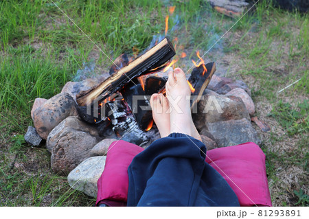 A young child puts its feet up to warm by the campfire 81293891