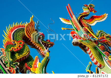 Amazing colorful Chinese figurines of two Dragons and Phoenix, one looking at the other in contrast to the super blue sky. 81297172