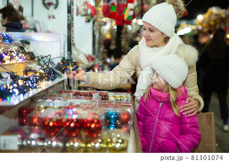 Happy mom and daughter buy Christmas fairy lights at the street market 81301074