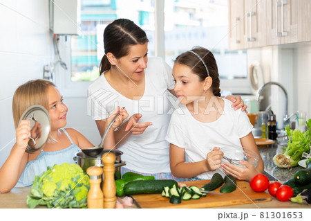 Young woman and two daughters cooking together Young woman and two daughters cooking together 81301653