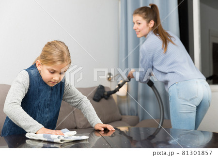 Woman with vacuum cleaner and daughter with rag 81301857
