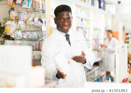 Portrait of african american male pharmacist in pharmacy demonstrating goods Portrait of african american male pharmacist in pharmacy demonstrating goods 81301862