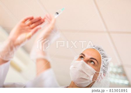 Nurse prepares a syringe for injection Nurse prepares a syringe for injection 81301891