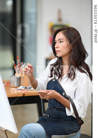 Portrait of beautiful female artist painting picture in her workshop. Portrait of beautiful female artist painting picture in her workshop. 81303596