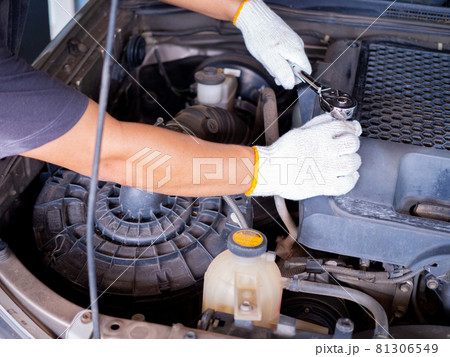 Mechanic holding a block wrench handle while fixing a car. 81306549