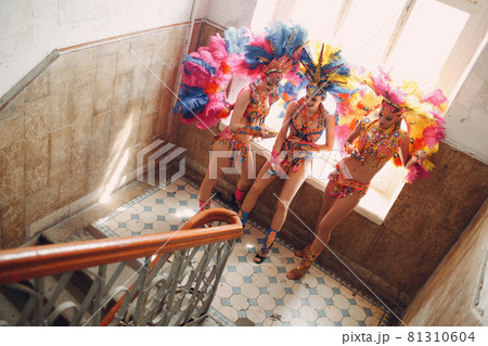 Woman in brazilian samba carnival costume with colorful feathers plumage relax in old entrance with big window 81310604