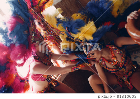 Woman in brazilian samba carnival costume with colorful feathers plumage relax in old entrance with big window 81310605