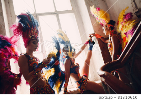 Woman in brazilian samba carnival costume with colorful feathers plumage relax in old entrance with big window 81310610
