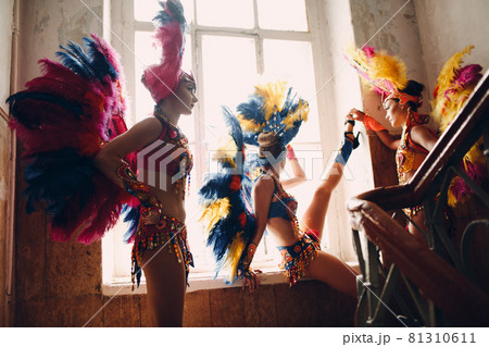 Woman in brazilian samba carnival costume with colorful feathers plumage relax in old entrance with big window 81310611