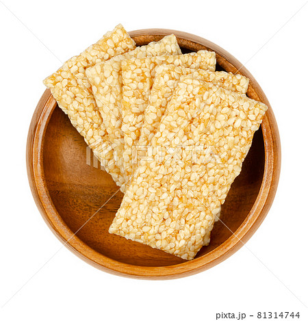 Sesame seed candy bars, in a wooden bowl. Sesame brittle or crunch, a confection of sesame seeds and honey pressed into flat bars, a popular snack in the Middle East. Close-up, from above, food photo. 81314744