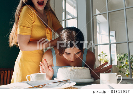 Young woman dips face in white cake with cream. Happy birthday concept. Young woman dips face in white cake with cream. Happy birthday concept. 81315917