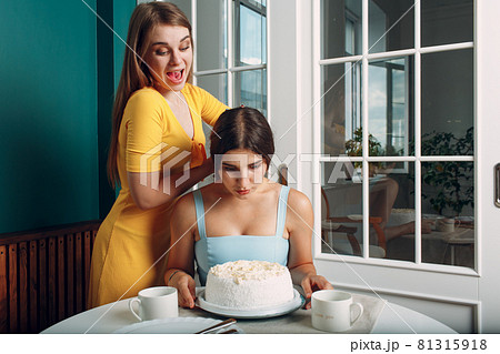 Young woman dips face in white cake with cream. Happy birthday concept. Young woman dips face in white cake with cream. Happy birthday concept. 81315918