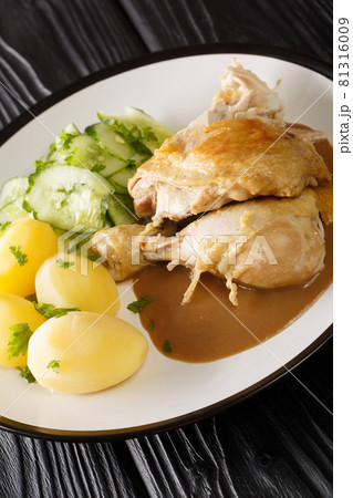 Gammeldags kylling translated as old-fashioned chicken served with potatoes, cucumber salad, and the accompanying sauce closeup in the plate. Vertical 81316009