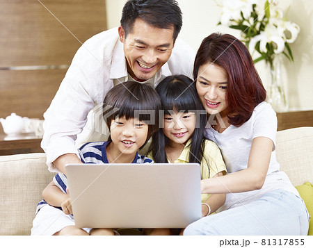 happy asian family with two children sitting on couch at home using laptop computer together 81317855