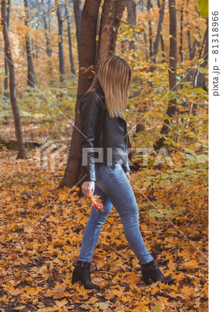 Lonely sad woman is kicking yellow leaves in autumn. Sad mood and seasonal affective disorder concept. Lonely sad woman is kicking yellow leaves in autumn. Sad mood and seasonal affective disorder concept. 81318966