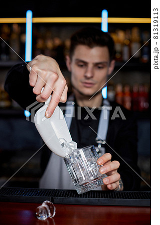 Barman puts the ice cubes into a glass Barman puts the ice cubes into a glass 81319113